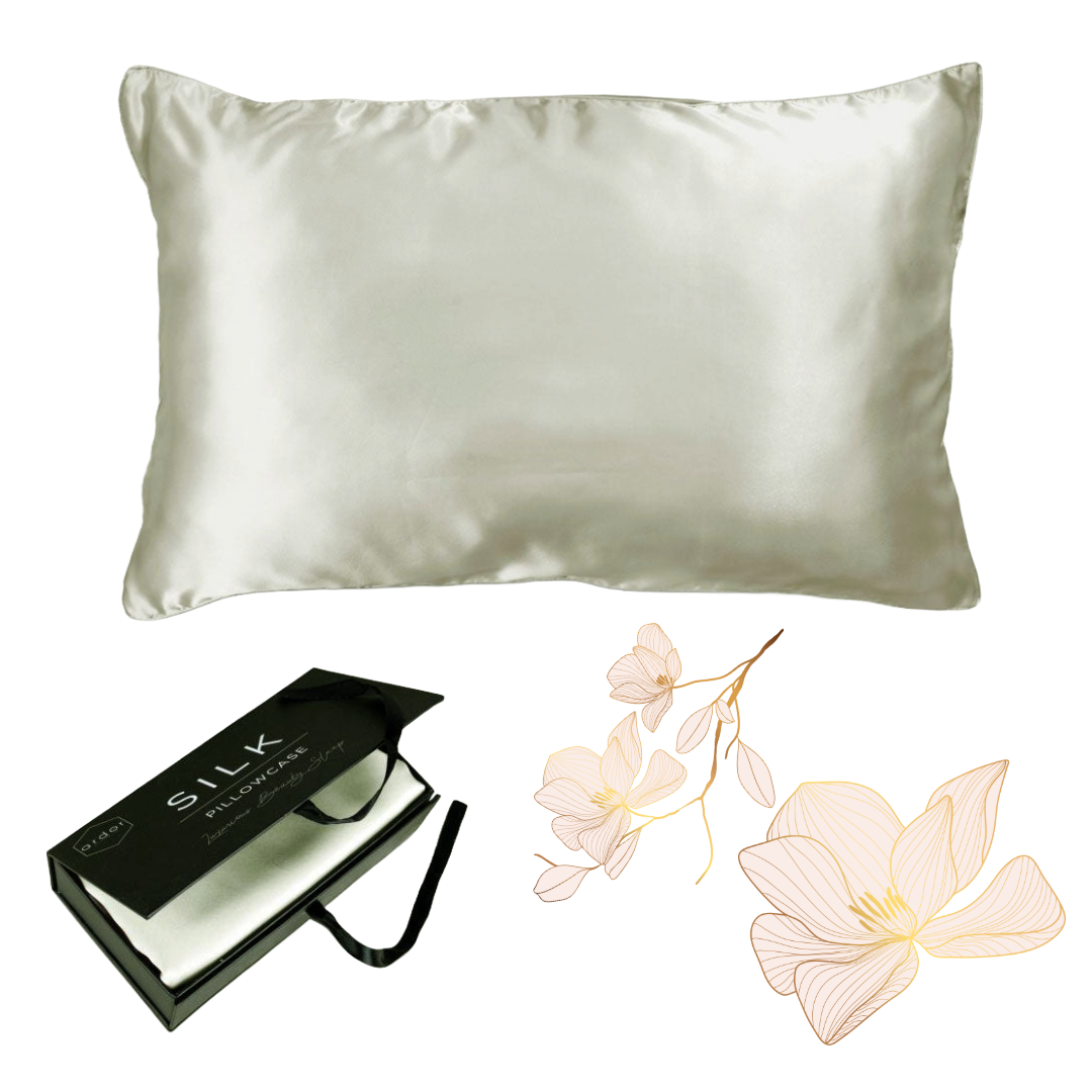 The Ardor Mulberry Silk Standard Pillowcase Silver Nights displayed alongside its packaging and a decorative flower, suggesting a luxurious and elegant product intended for comfort and style in bedroom decor.