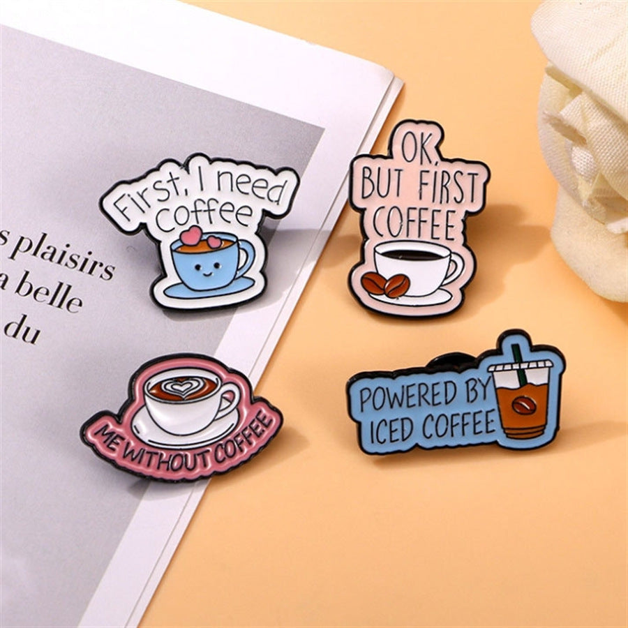 The Coffee Lover Enamel Pin Set 4 Pack – Cute Coffee Cup Lapel Pins for Bags, Jackets & Accessories featuring four coffee-themed pins such as 'Me without coffee' on a surface with a magazine and decorative item.