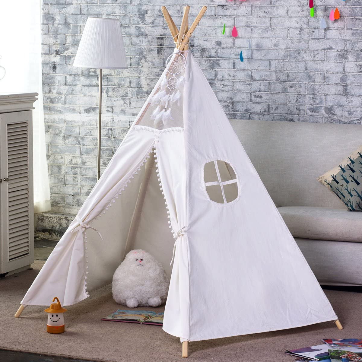 The Giant Teepee Playhouse Tent in Natural Canvas texture, set up indoors. It features wooden poles and a flap door, with a small plush toy inside.