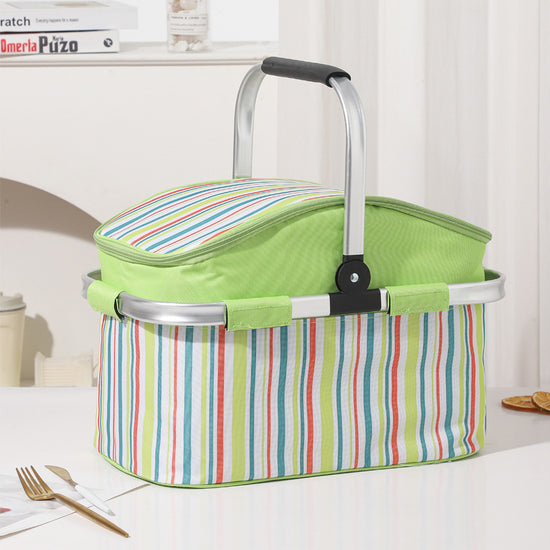 Green striped picnic basket with a handle on a table.
